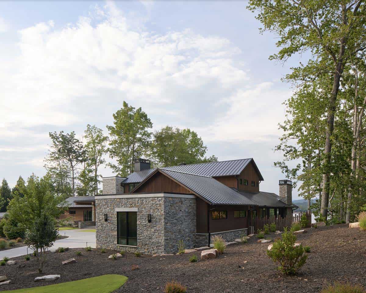 Side exterior view of the stone entry tower and gabled metal roof surrounded by landscaping