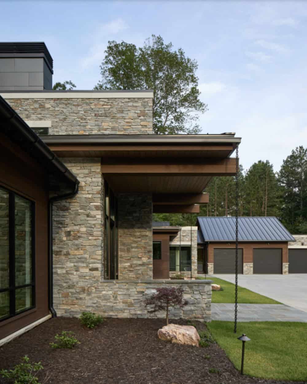 Corner view of the stone entry tower's cantilevered roof overhang with garage in the background