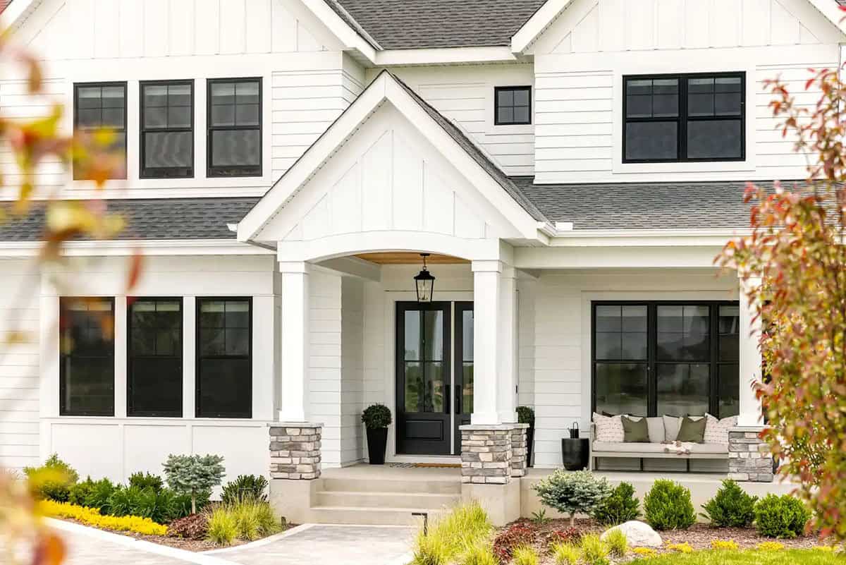 White farmhouse home with arched front porch entry and black double doors