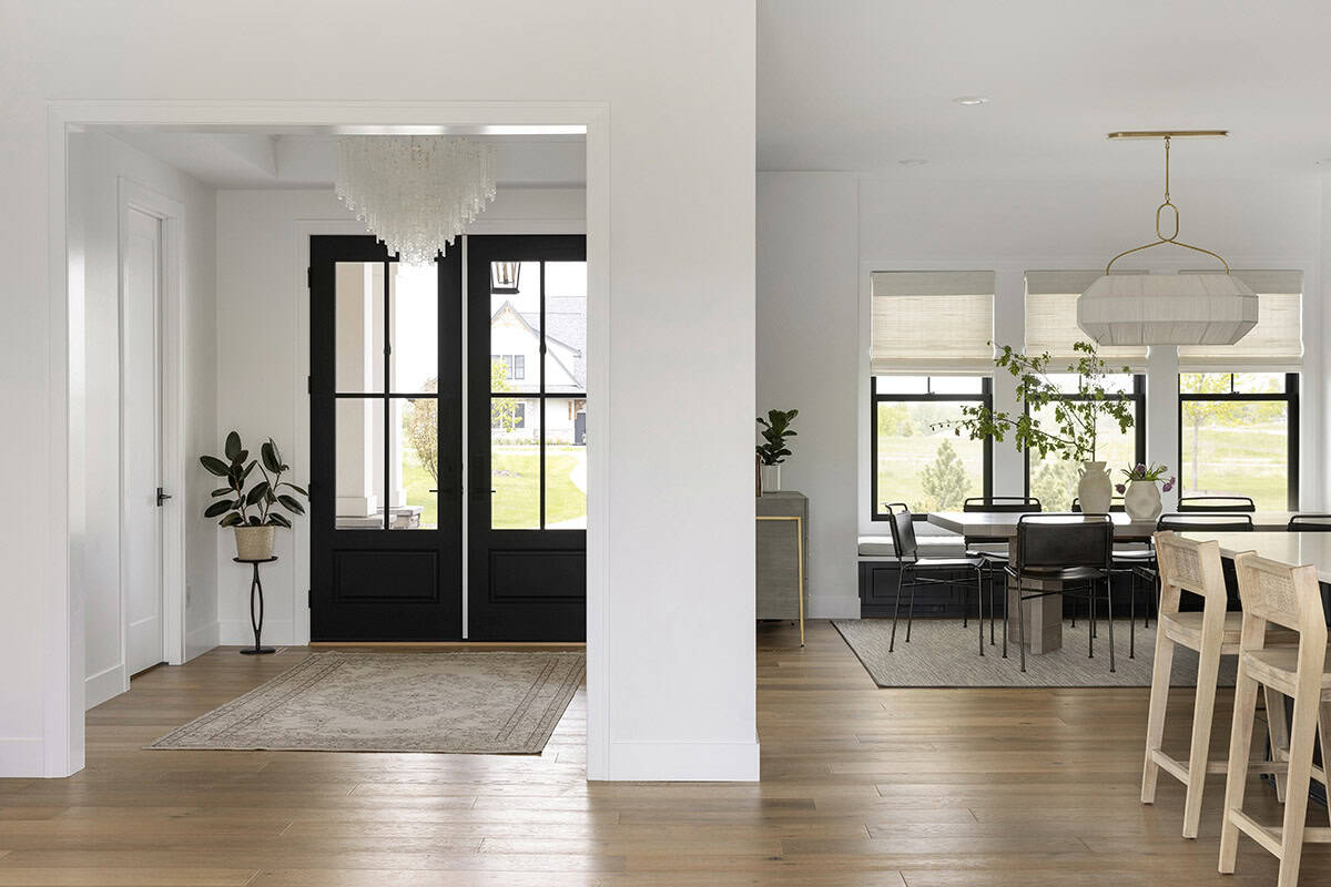 Entryway with black front door and glass chandelier opening to dining area