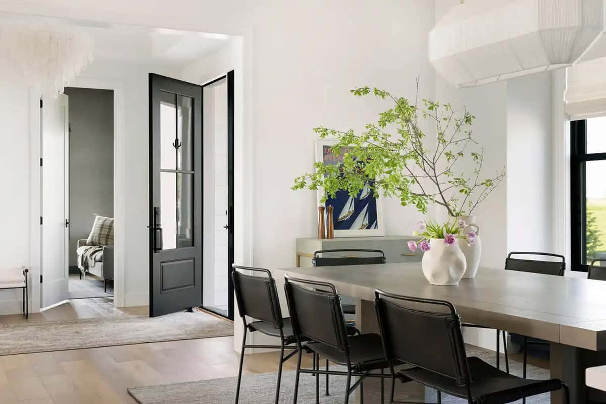 Black french door leading into dining room with wood table and black chairs