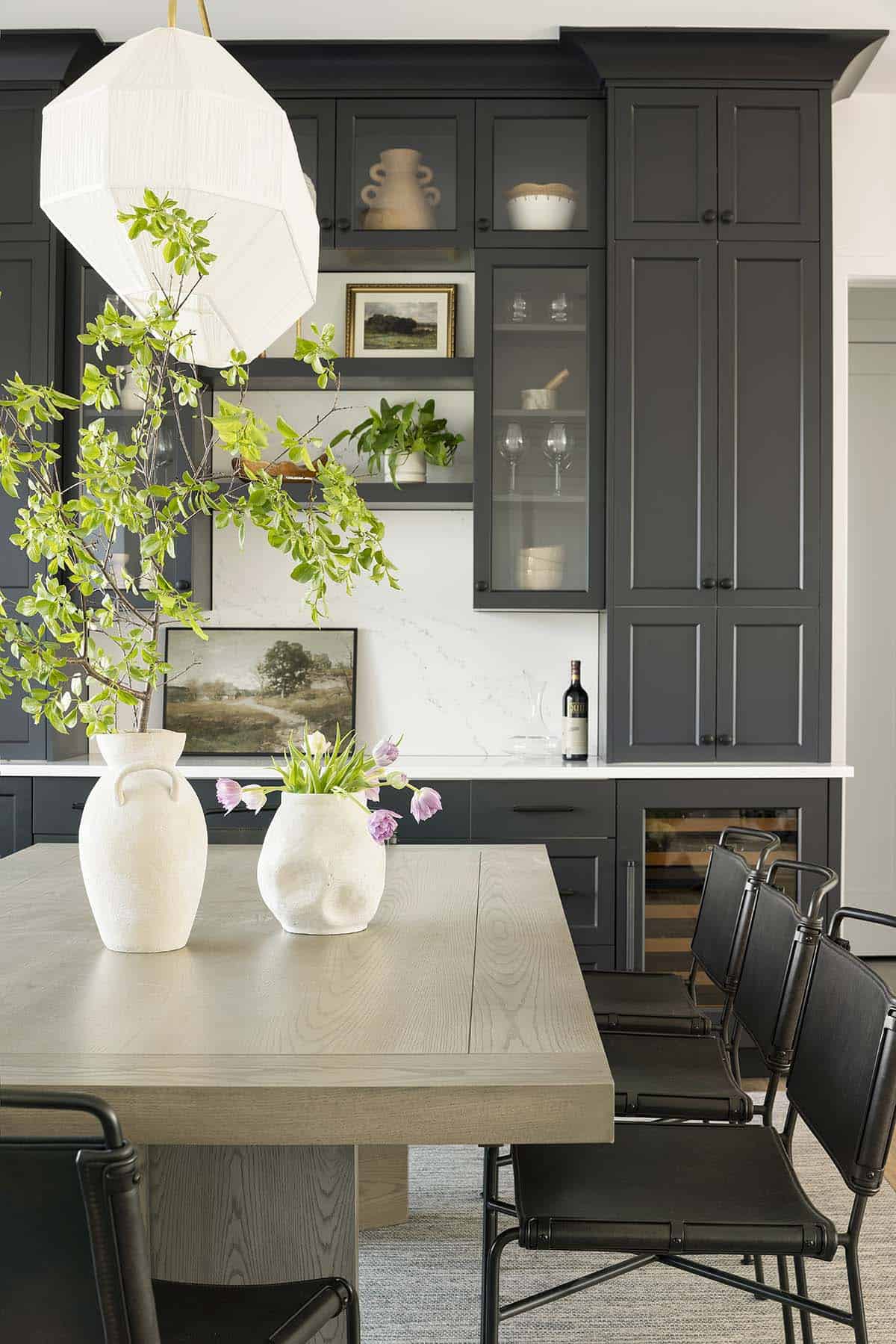 Dark dining room built-ins with glass cabinet doors and white vases