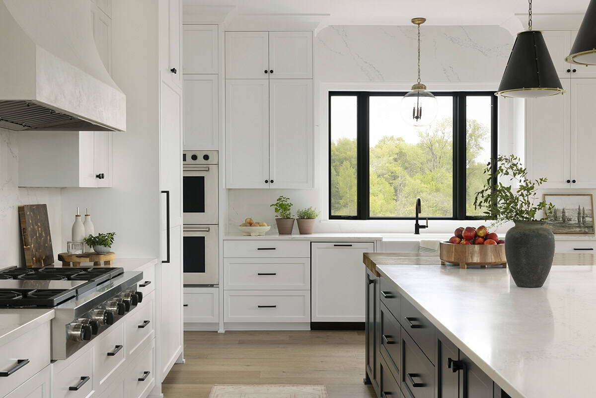 Kitchen with stainless range, white cabinetry, and black-framed window