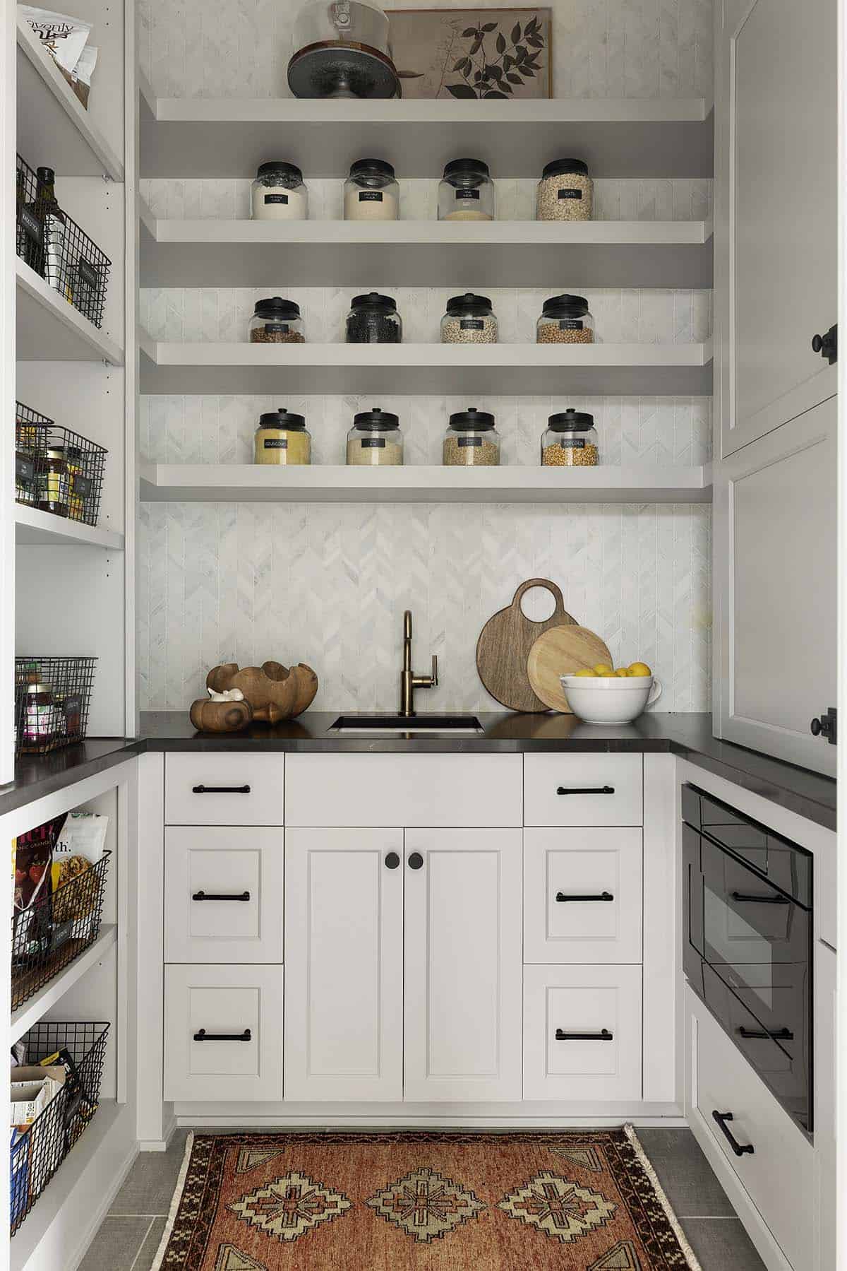 Walk-in pantry with herringbone tile backsplash and glass storage jars
