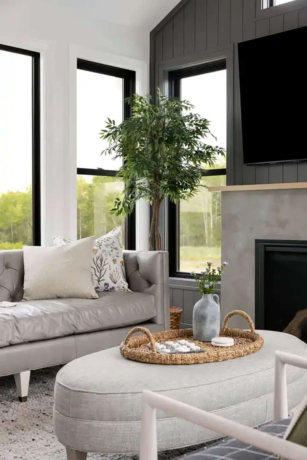 Sunroom with gray leather sofa and round upholstered ottoman