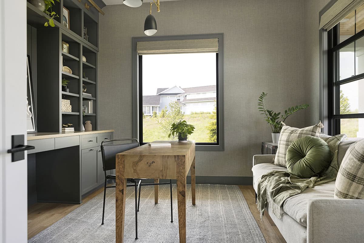 Home office with wood desk, gray built-in shelving, and window view