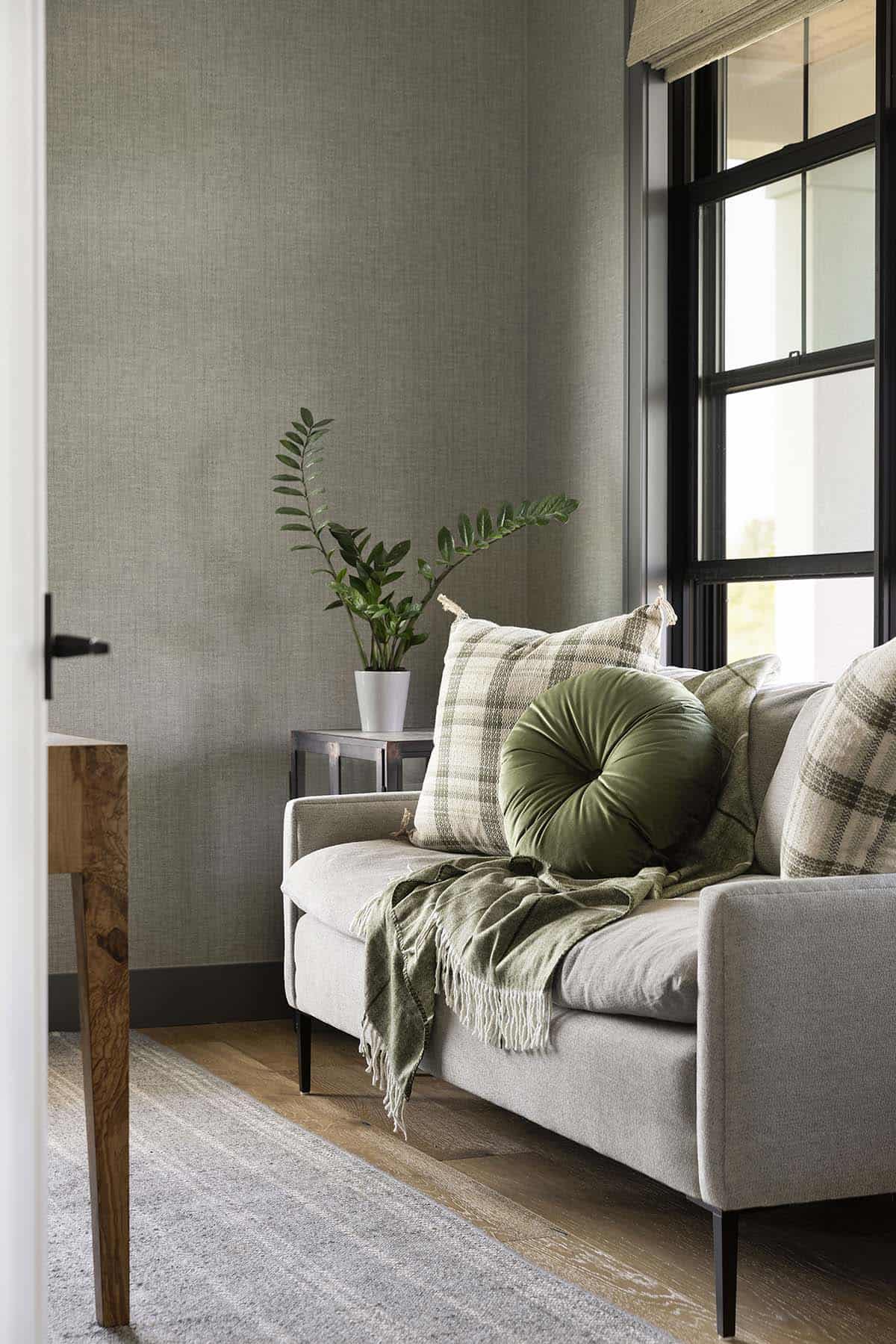 Sunroom sofa corner with plaid pillows and green throw blanket