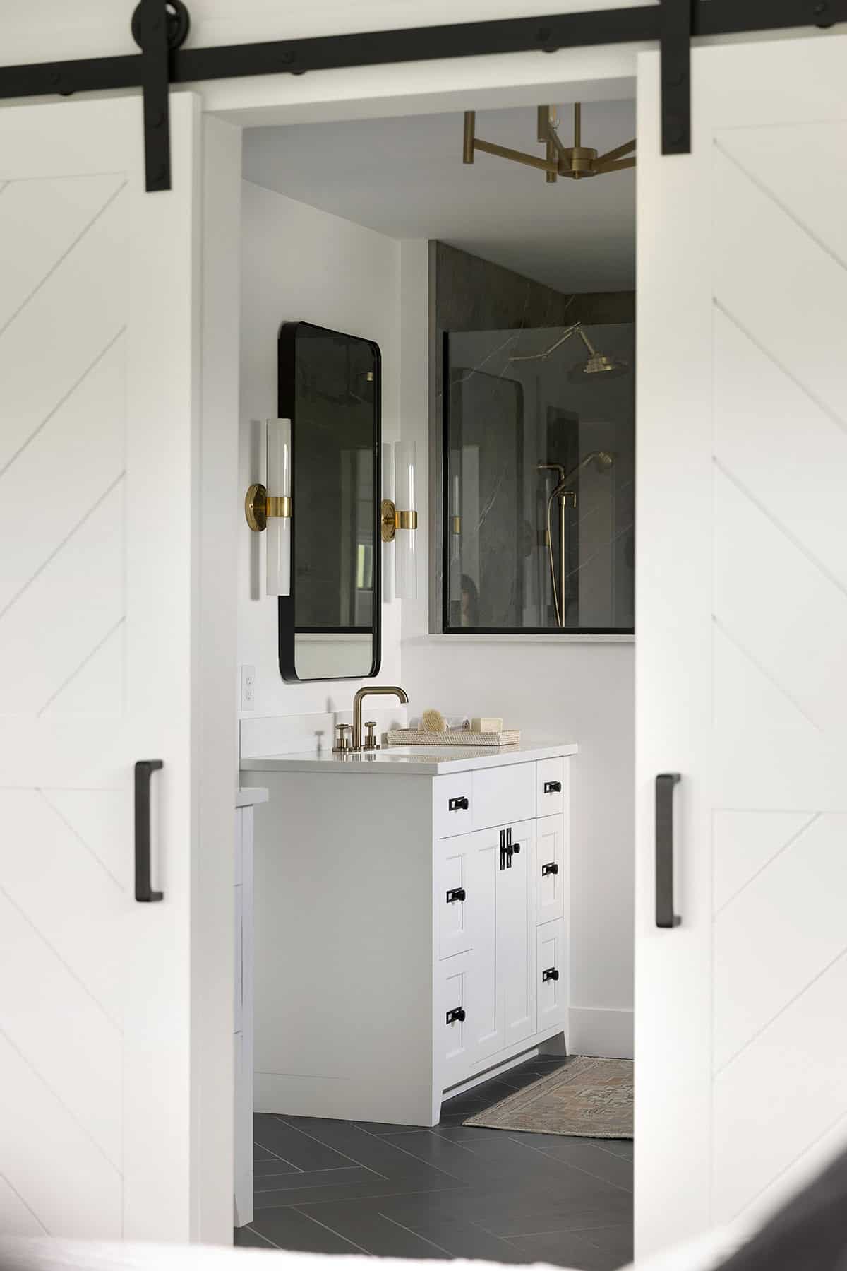 View through barn doors into bathroom vanity and walk-in shower