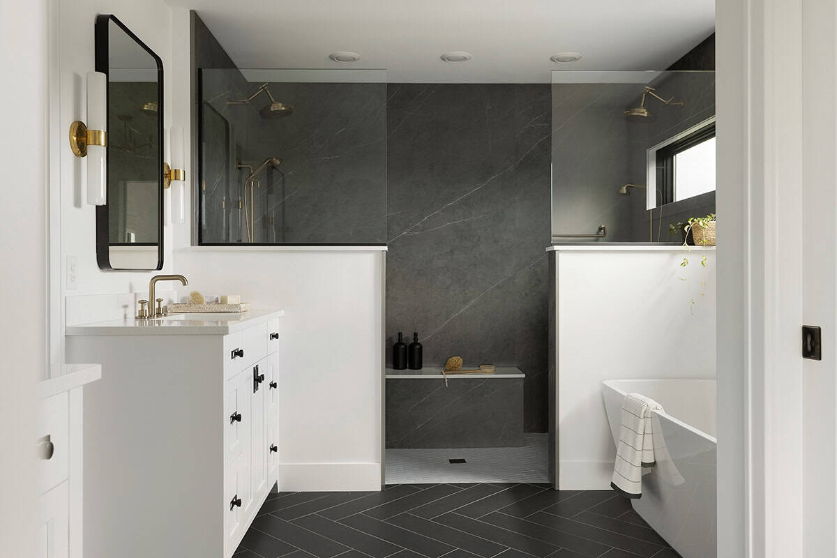 Bathroom with dark tile shower, freestanding tub, and white vanity