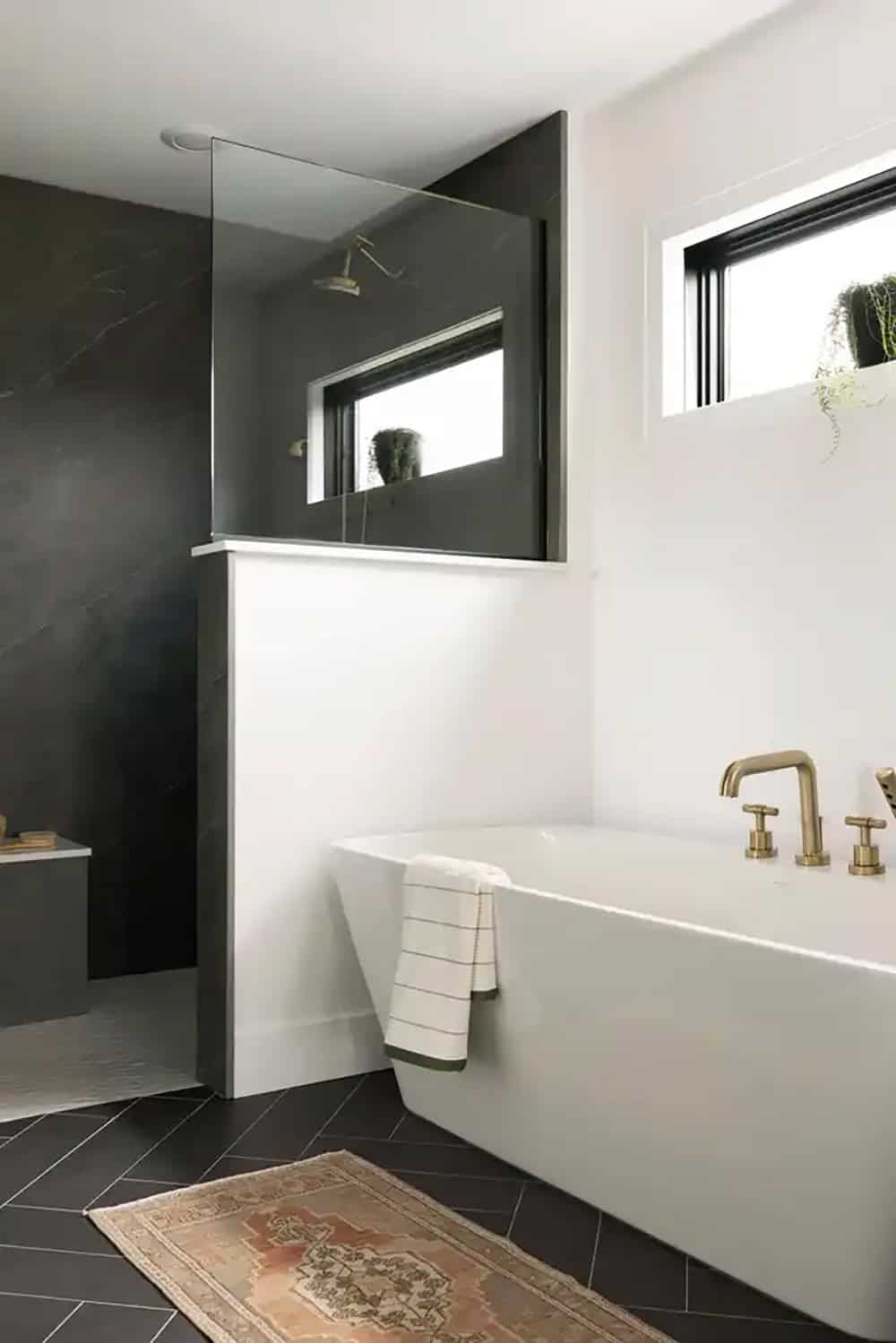 Freestanding soaking tub with brass fixtures and glass shower wall