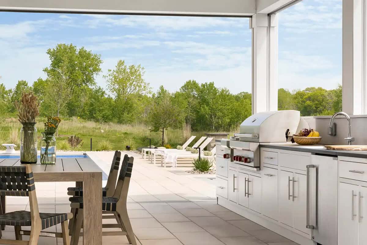 Outdoor kitchen counter with grill overlooking pool and lawn