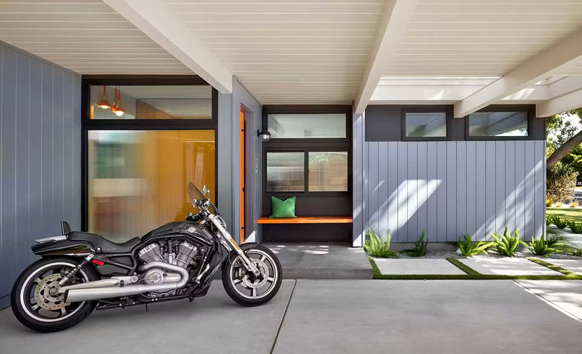 Motorcycle parked under carport beside orange front door