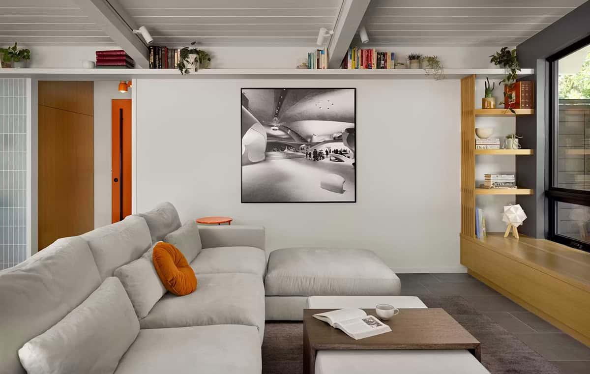Gray sectional sofa with orange throw pillow and artwork