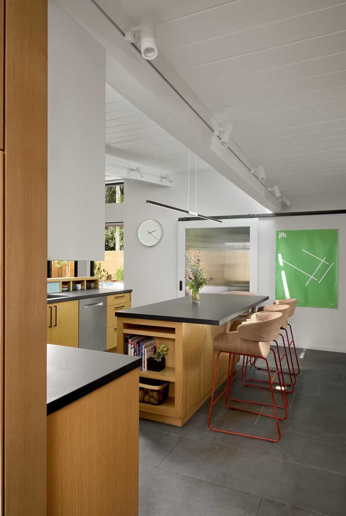 Oak kitchen island with red bar stools and green artwork