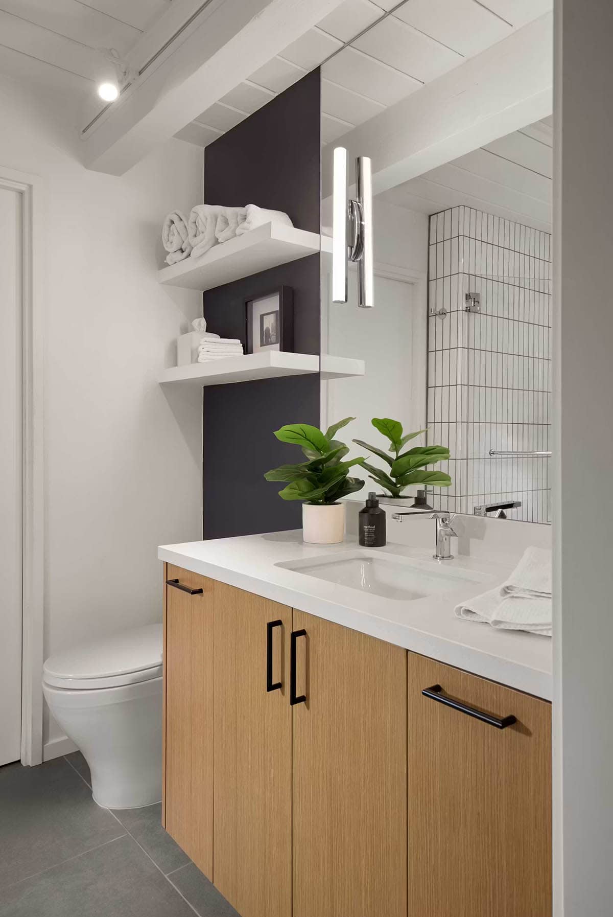 White vanity with oak cabinetry and dark accent wall