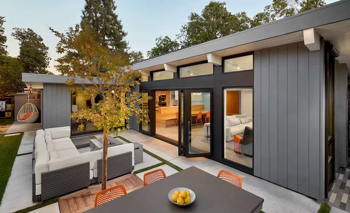 Eichler home exterior at dusk with lit interior and patio