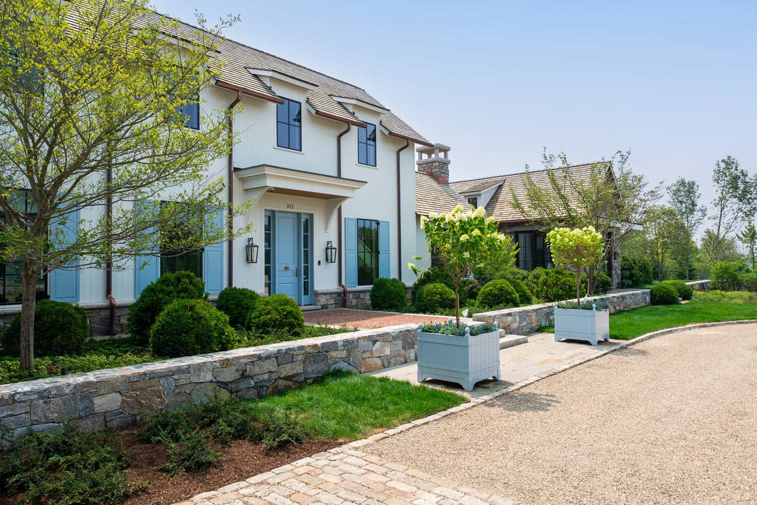 Front exterior with blue shutters, stone chimney, and cedar shake roof