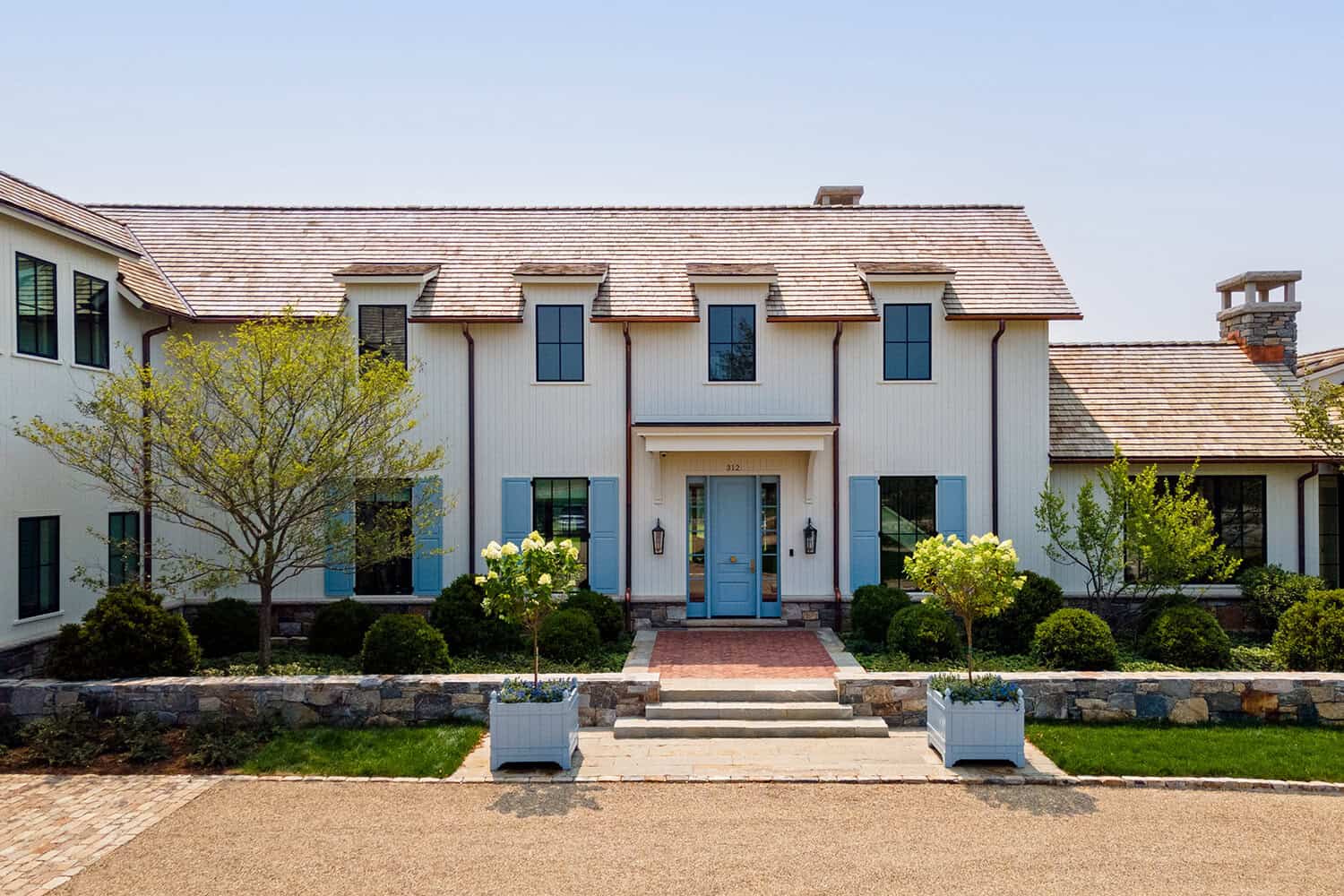Symmetrical farmhouse facade with blue front door and dormer windows