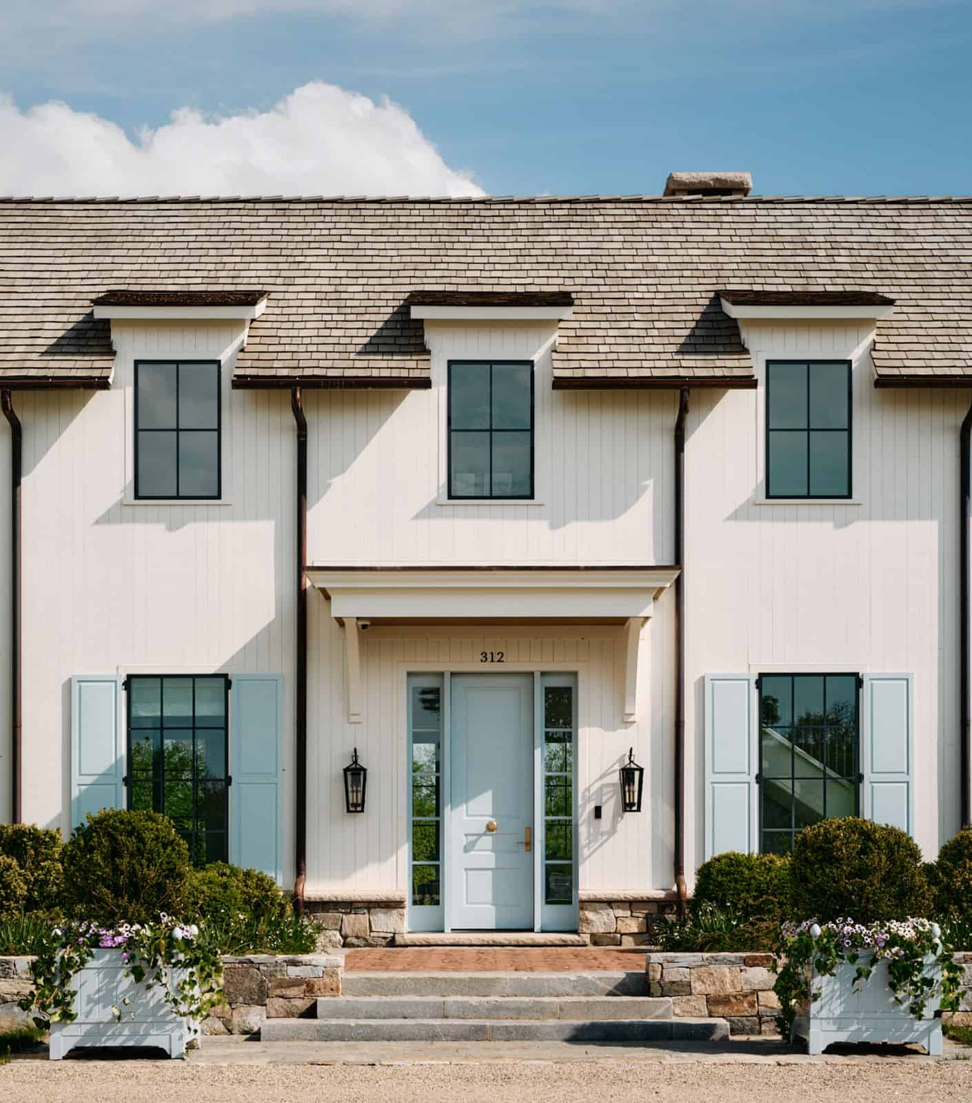 Front door detail with pale blue shutters and stone foundation