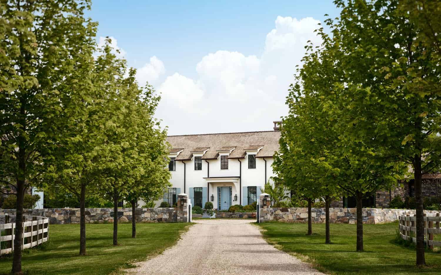 Tree-lined gravel drive leading to farmhouse with stone fencing