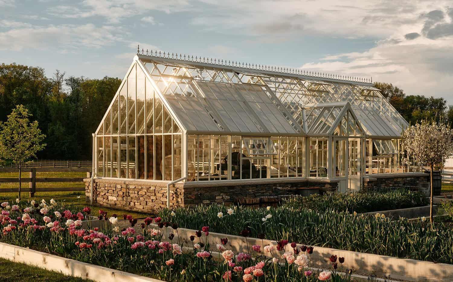 Glass greenhouse on stone base with tulip garden beds