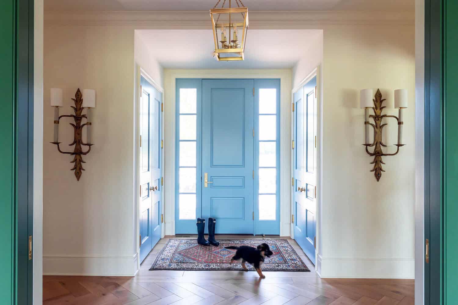 Entry foyer with blue front door and herringbone wood floor
