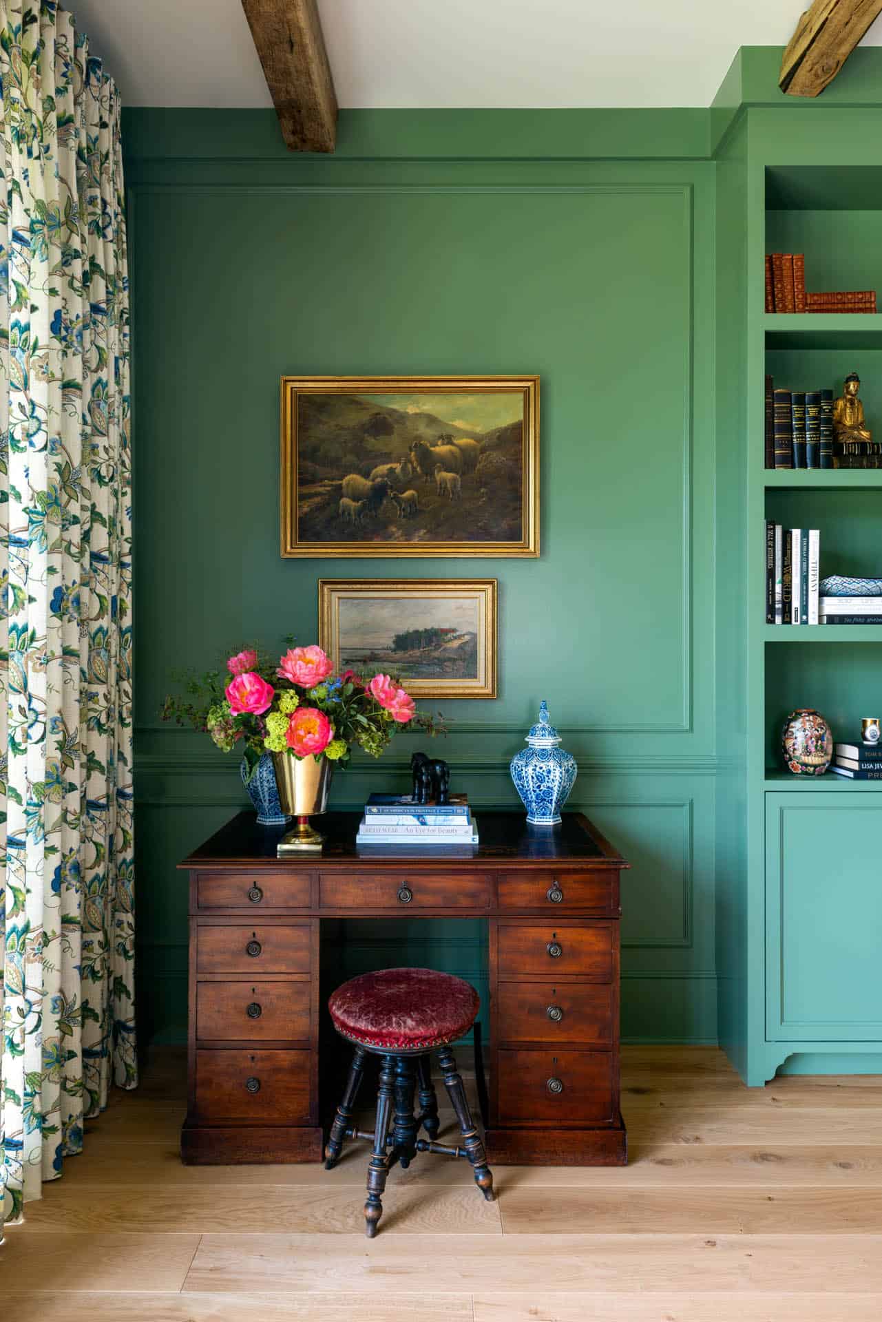 Antique desk vignette in green paneled room with gallery art