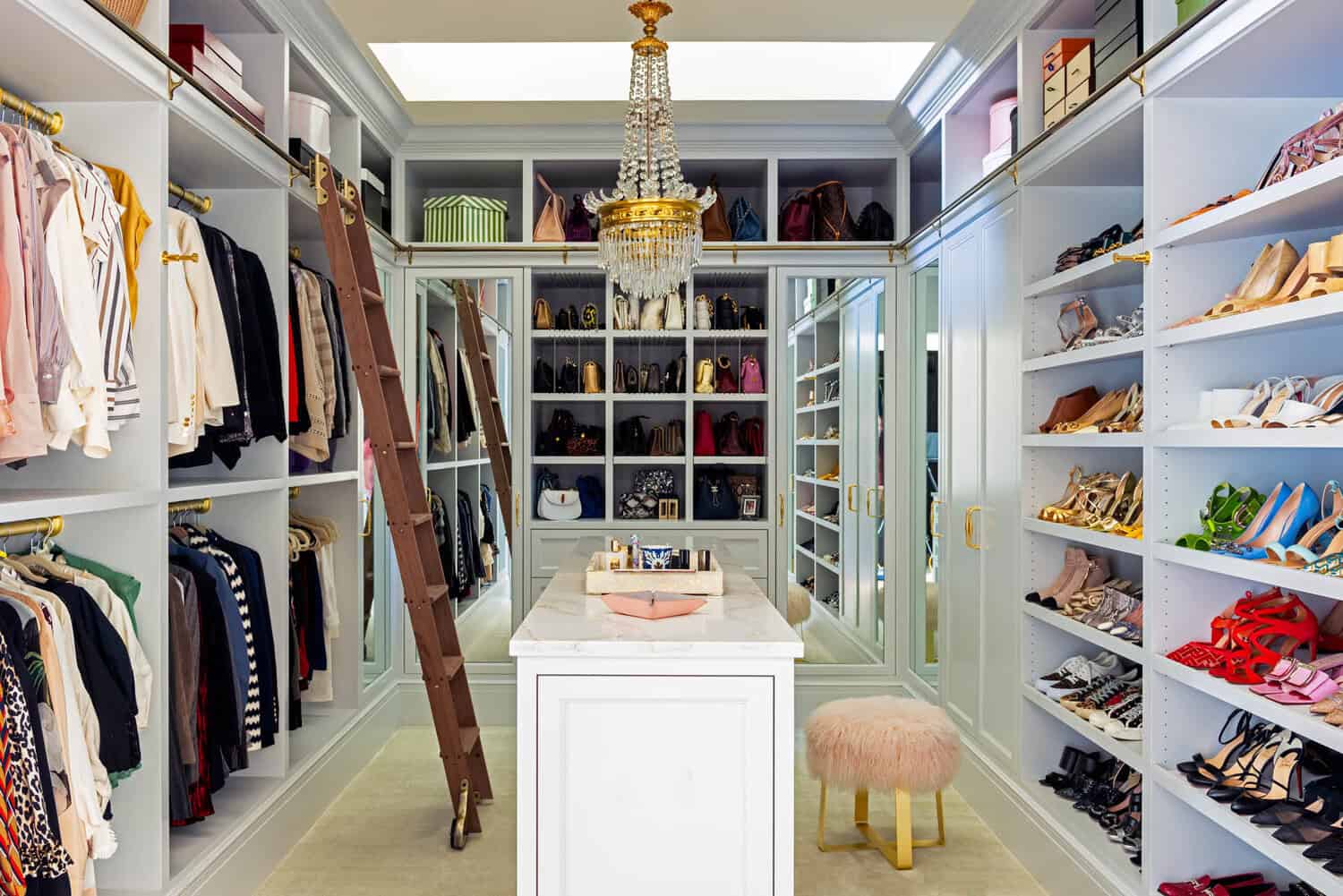 Walk-in closet with crystal chandelier and glass display shelves