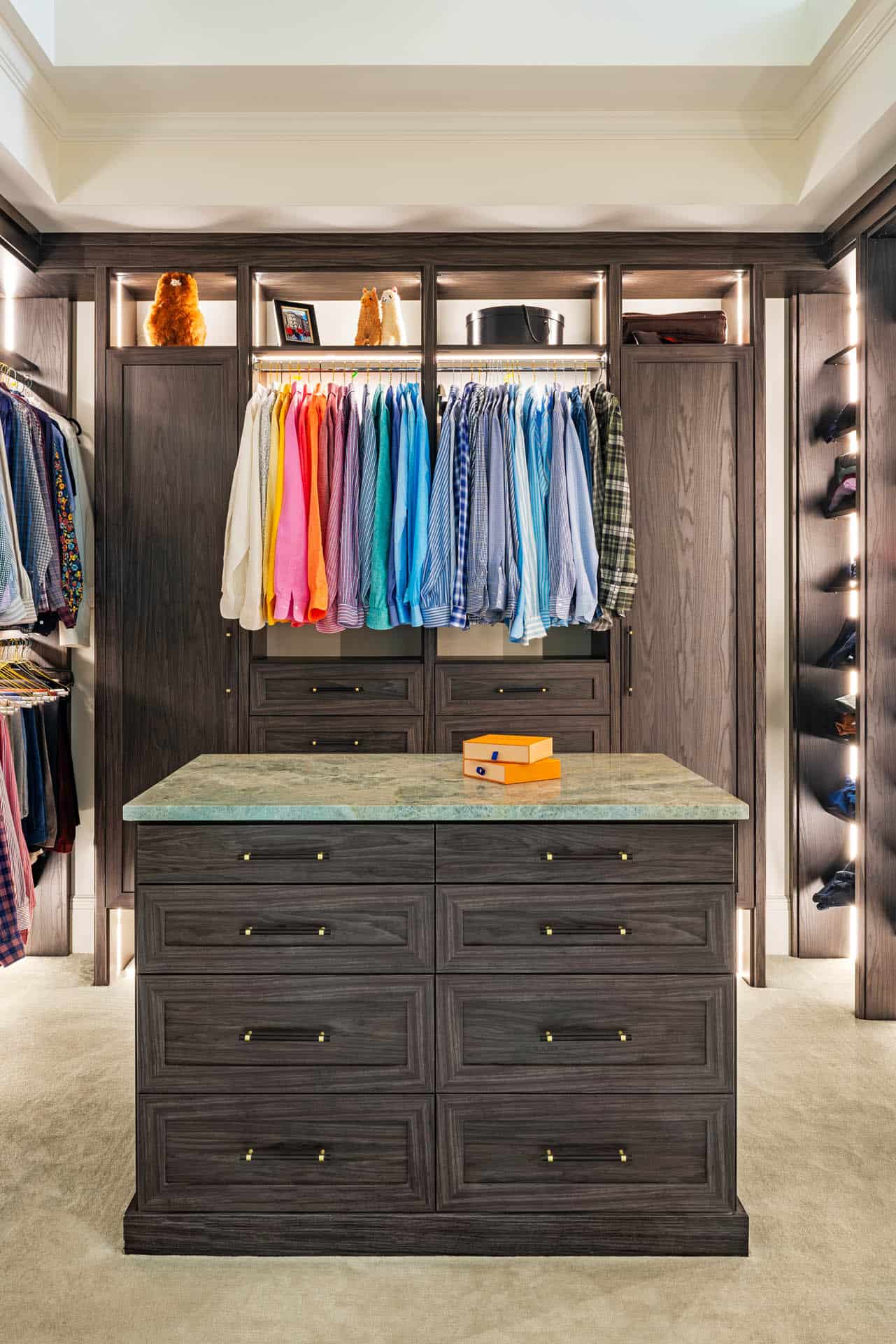 Men's closet with color-coded shirts and marble-top island
