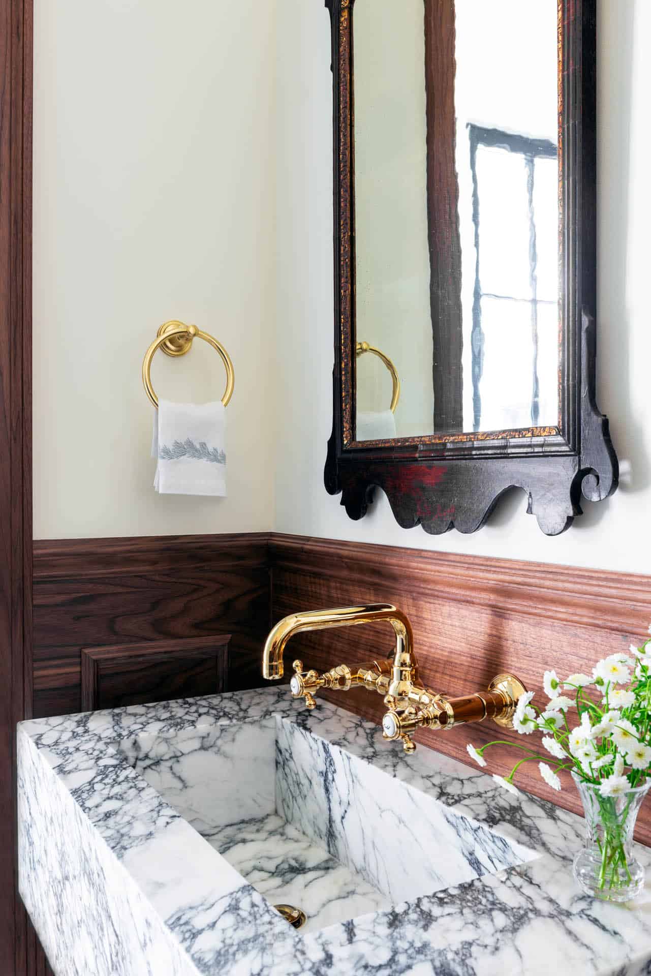 Powder room vanity with brass fixtures and antique mirror