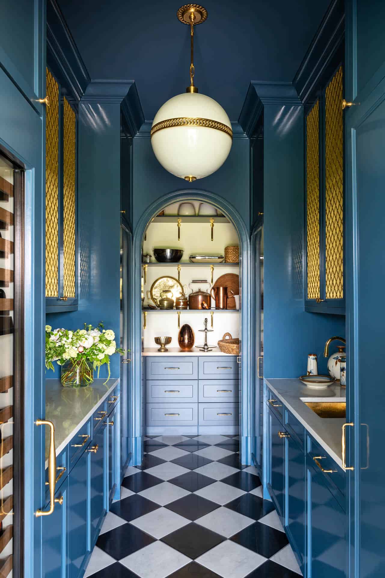 Blue lacquered pantry with checkerboard floor and brass hardware