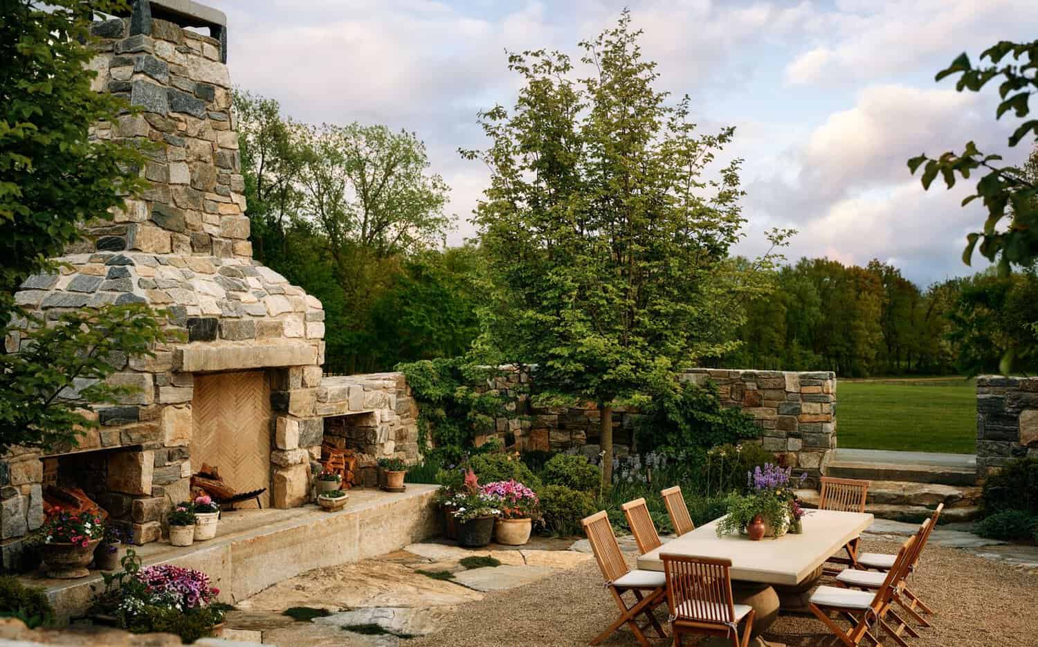 Stone fireplace detail with garden dining terrace and lawn view