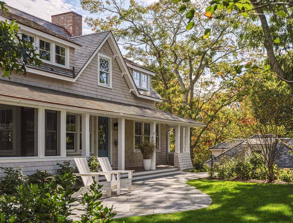 Screened porch corner with cedar shingle siding, gabled dormers, and Adirondack chairs on bluestone patio