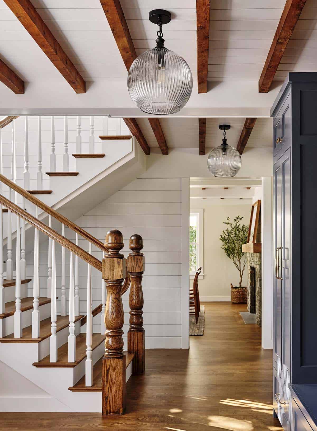 Staircase with turned wood newel posts, white balusters, and glass globe pendant lights