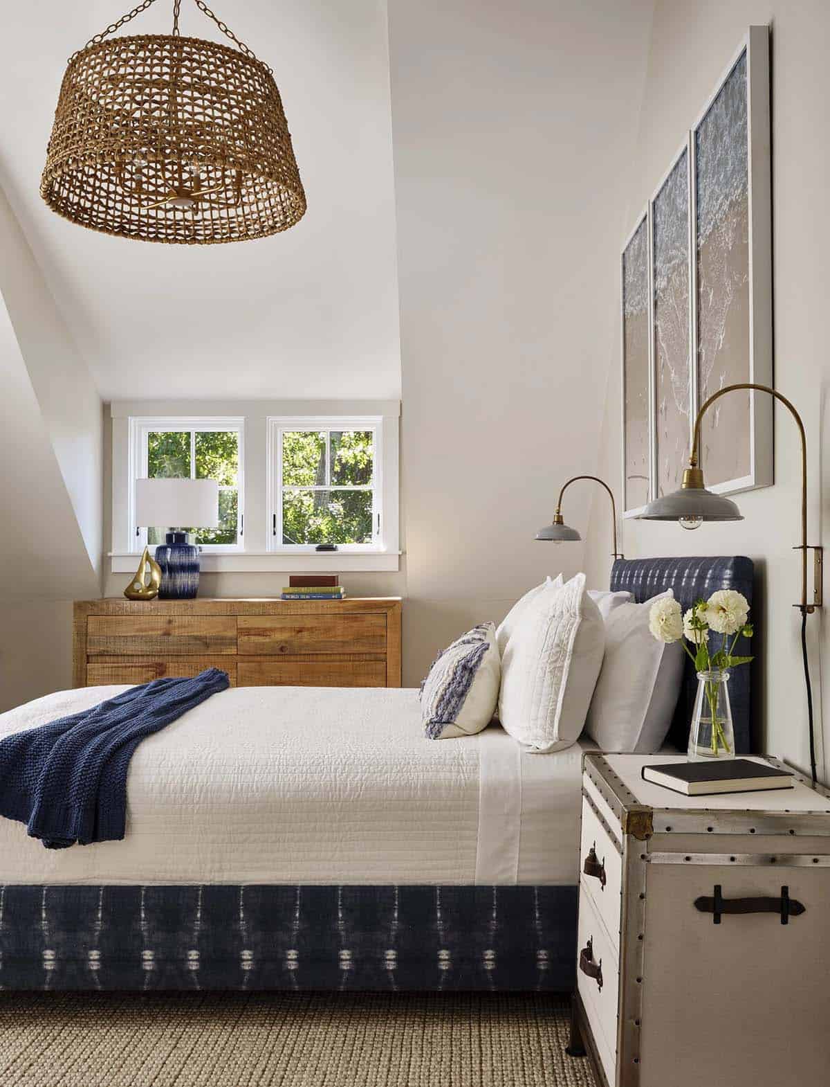 Bedroom with navy upholstered headboard, woven pendant light, and vintage trunk nightstand