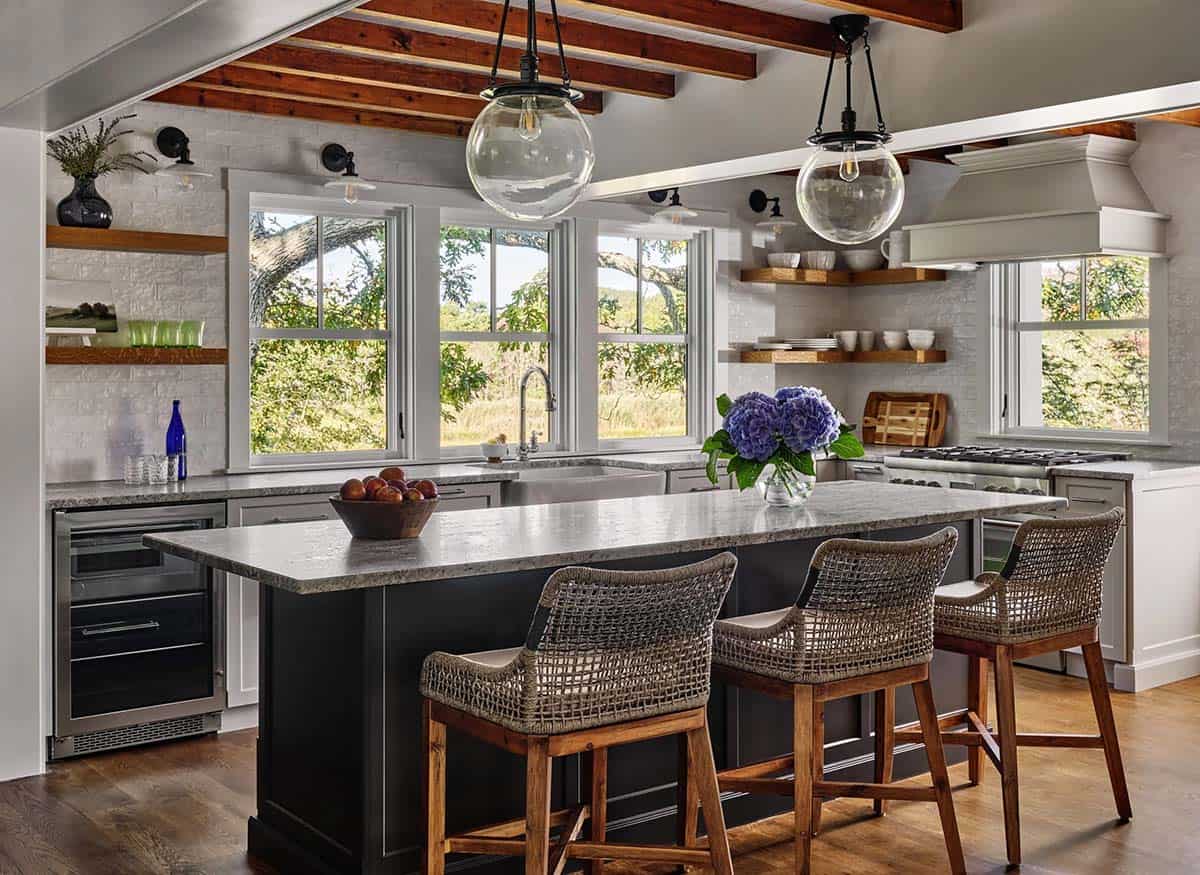 Kitchen island with woven counter stools, exposed wood beams, and glass globe pendant lights