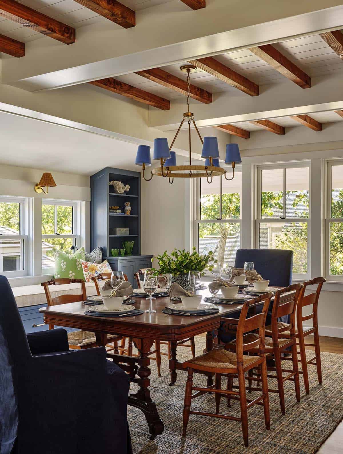 Dining room with wood table, blue slipcovered chairs, and rope-wrapped chandelier with blue shades