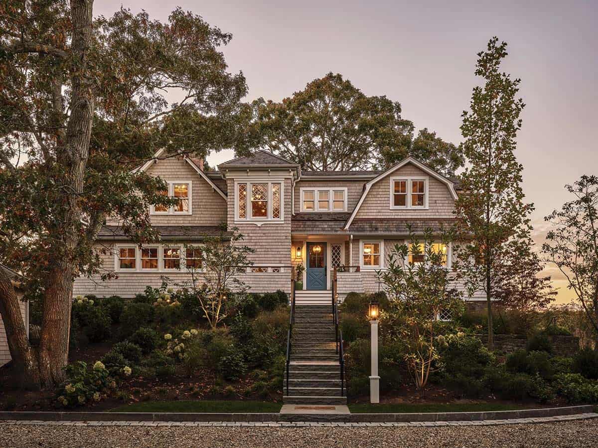 Twilight view of shingle-style home with illuminated windows and blue front door