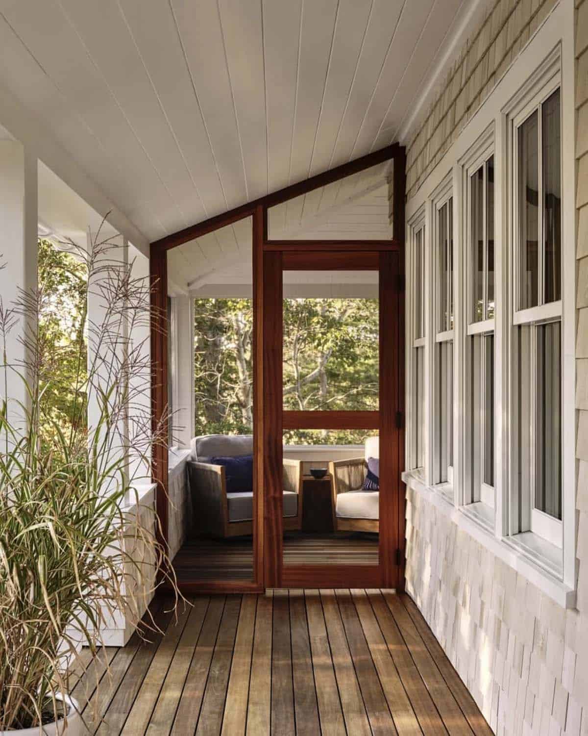 Screened porch entry with mahogany-framed door, teak chairs, and cedar shingle wall