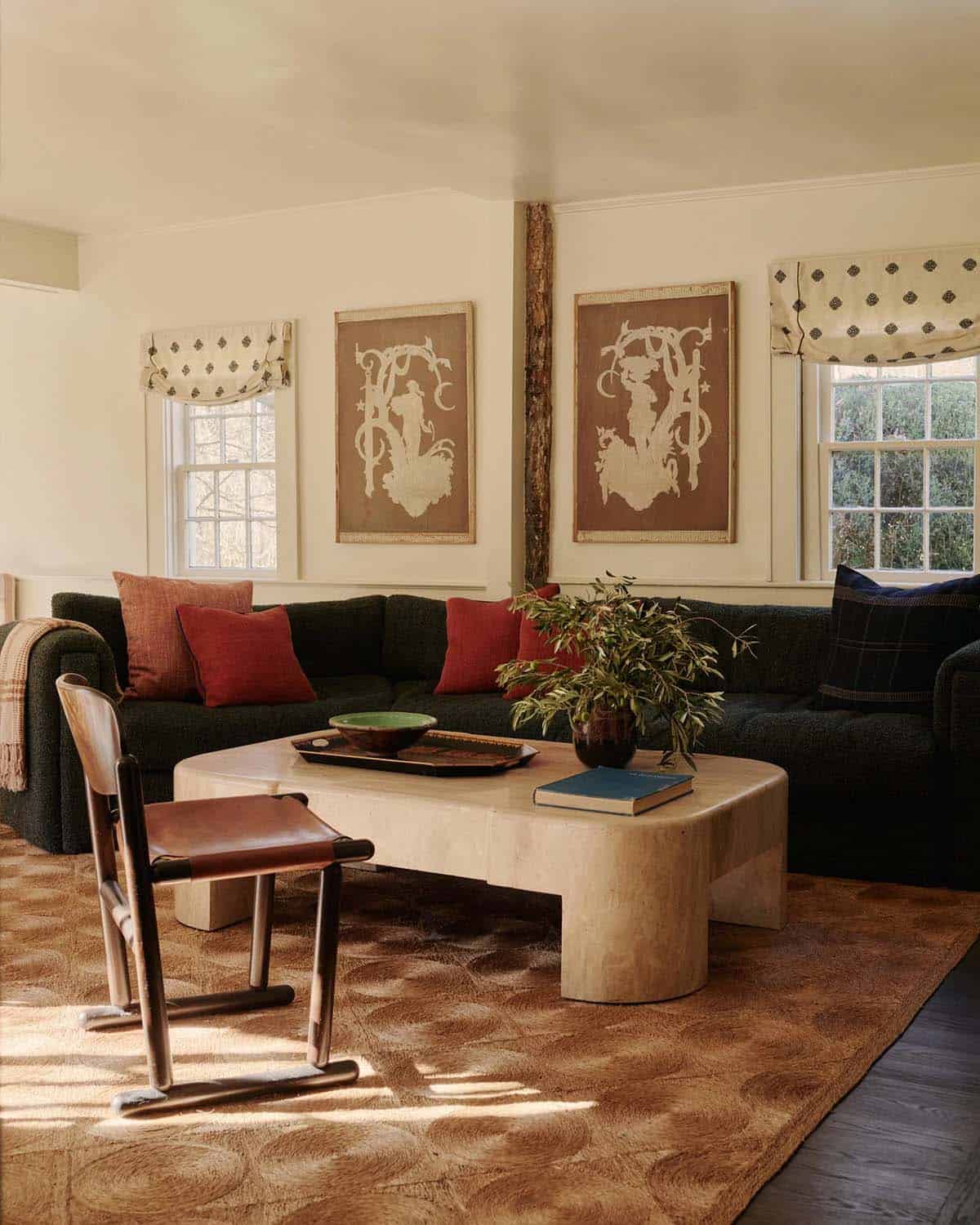 Living room with dark green sectional, red throw pillows, and travertine coffee table