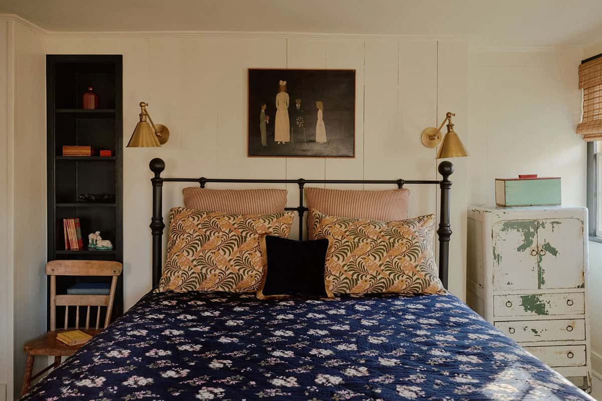 Bedroom with black iron bed frame, floral pillow shams, and distressed dresser