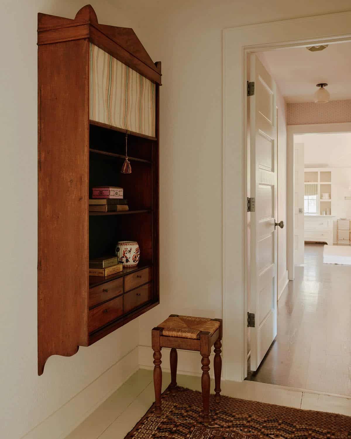 Hallway with antique wall-mounted cabinet and woven rush stool