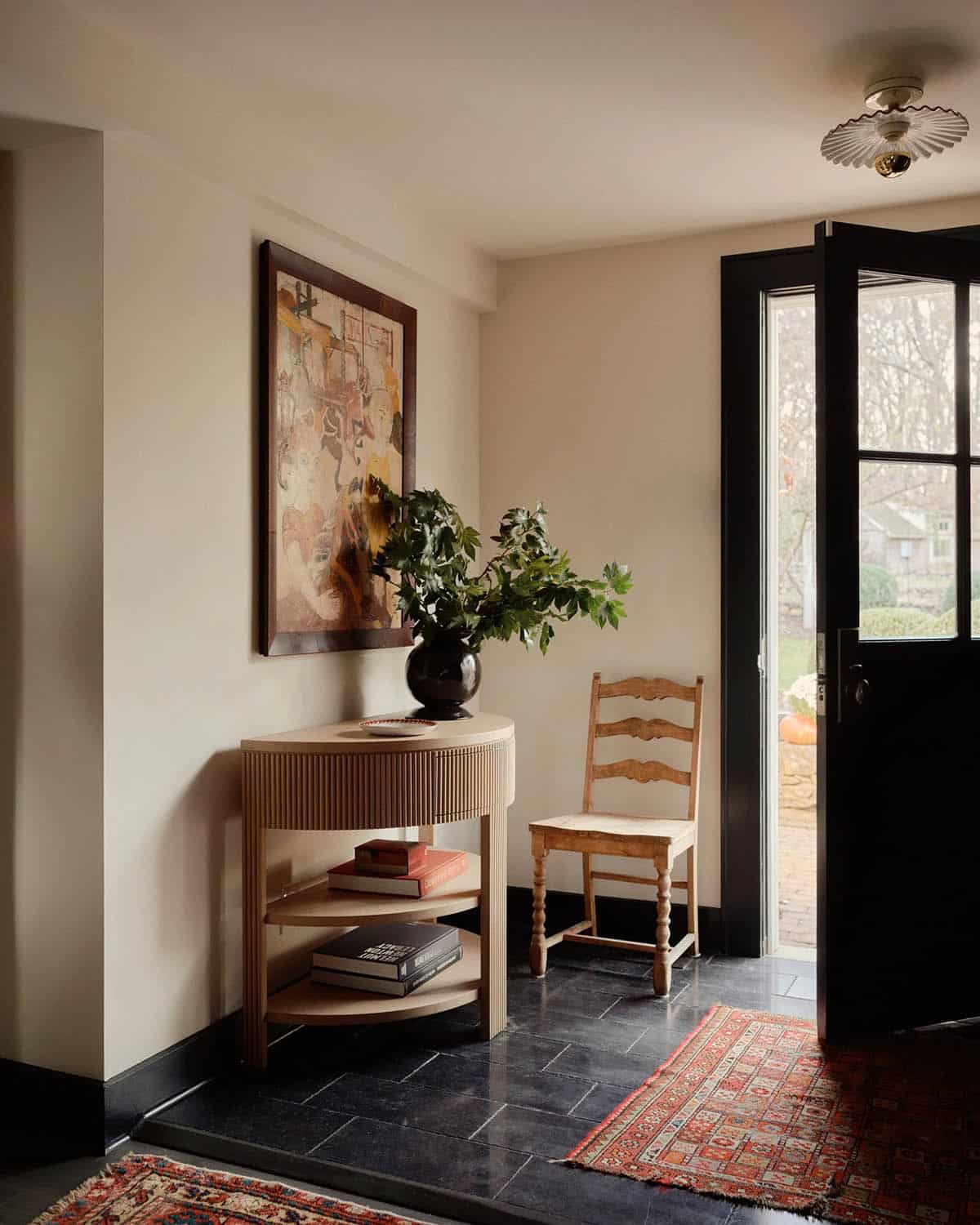 Entryway with reeded wood console table, ladder-back chair, and slate floor