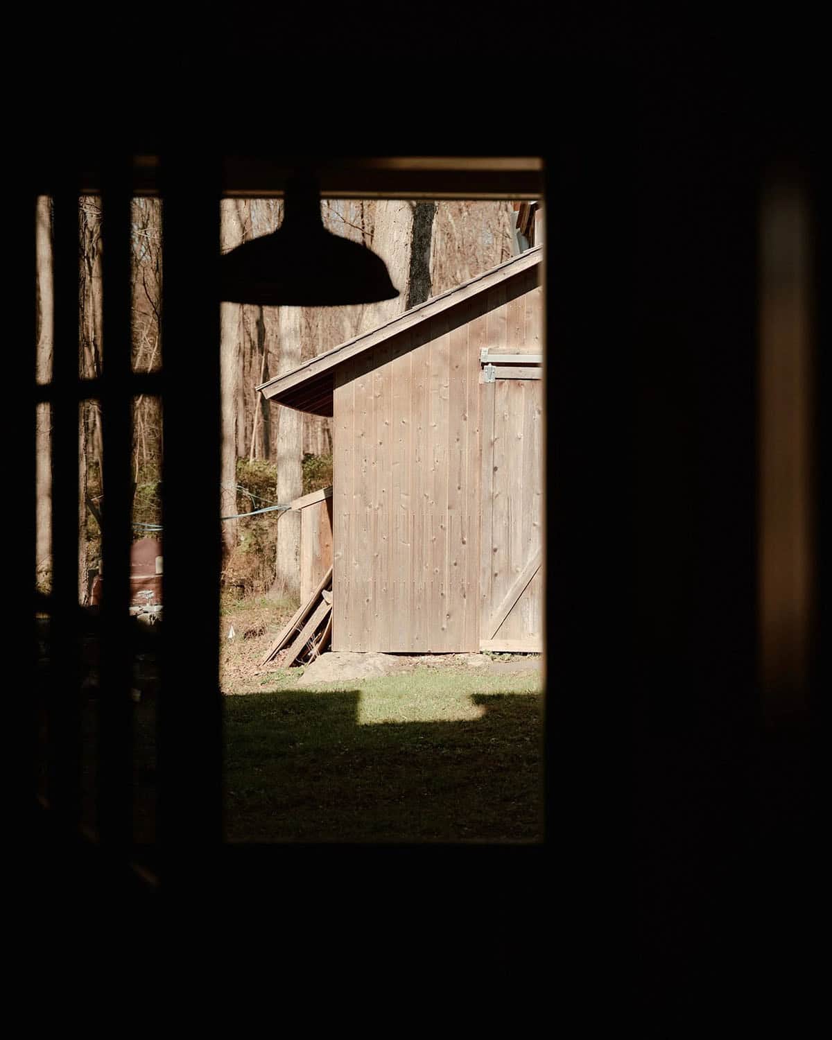 View through barn doorway of weathered wood shed and bare trees