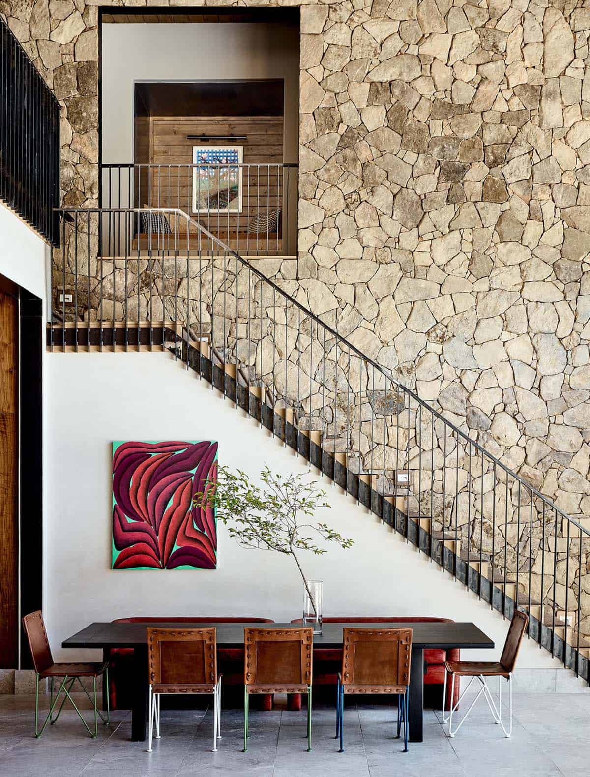 Stone staircase wall with leather dining chairs and colorful modern art