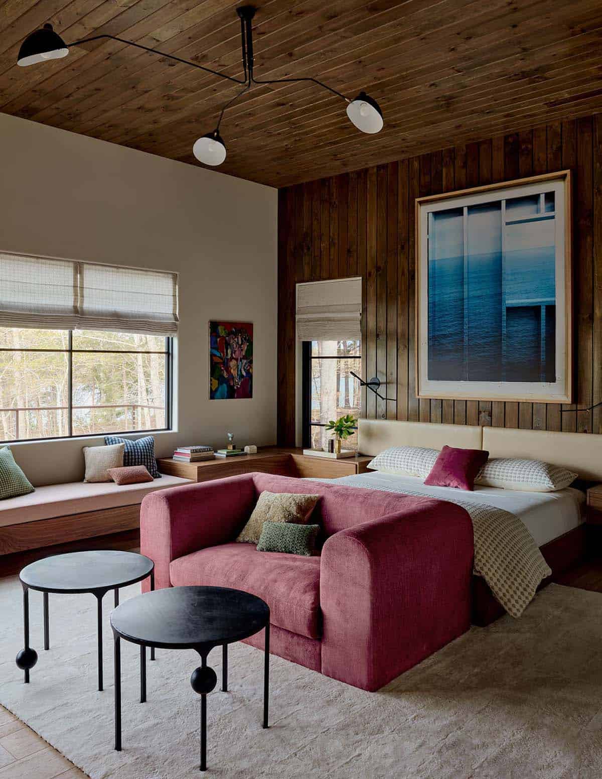 Primary bedroom with burgundy loveseat and wood paneled accent wall