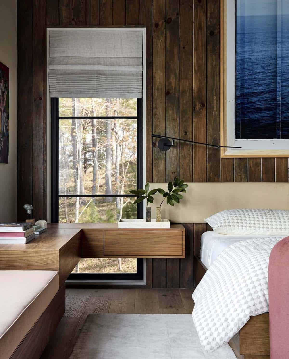 Bedroom nightstand nook with linen shade and forest view window
