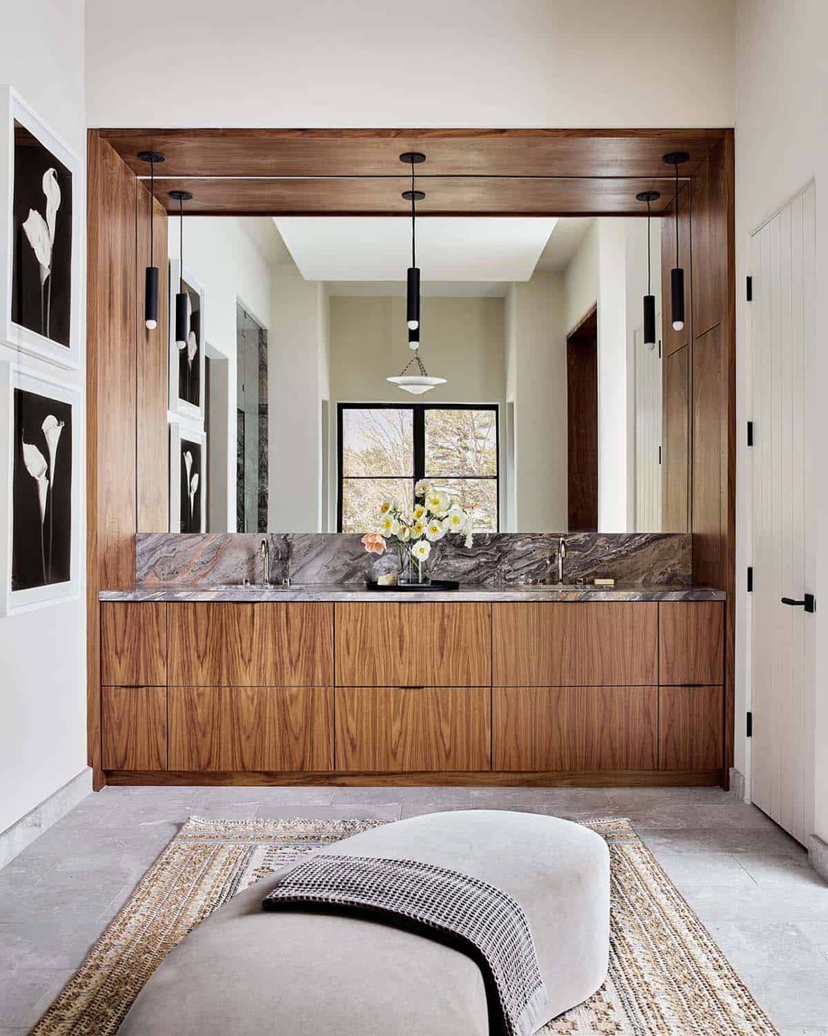 Wood vanity with mirror and patterned stone backsplash in bathroom