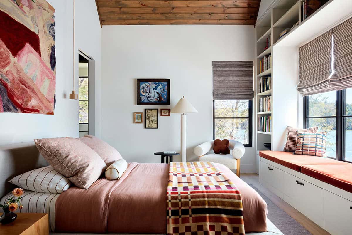 Guest bedroom with pink linens and built in bookshelf window seat