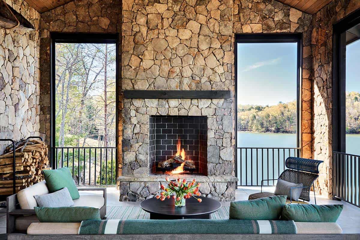 Covered stone porch with fireplace and green cushioned lake view seating